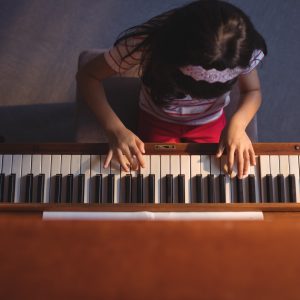 Overhead view of elementary girl playing piano in classroom